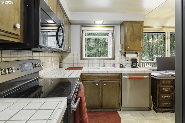kitchen featuring tile counters, decorative backsplash, a sink, and stainless steel appliances