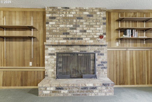 room details featuring wood walls, a textured ceiling, carpet, and a fireplace