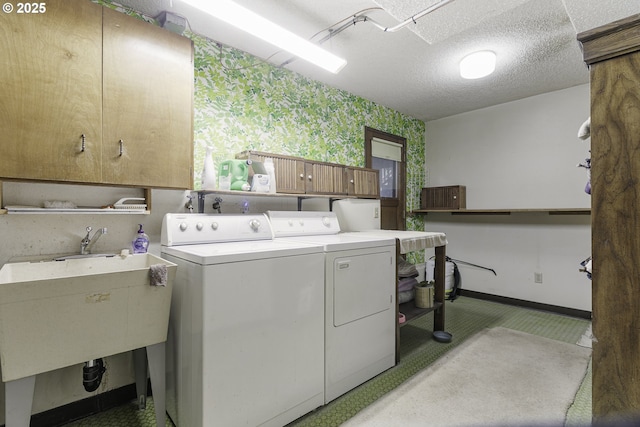 laundry area featuring baseboards, a textured ceiling, wallpapered walls, cabinet space, and washing machine and dryer