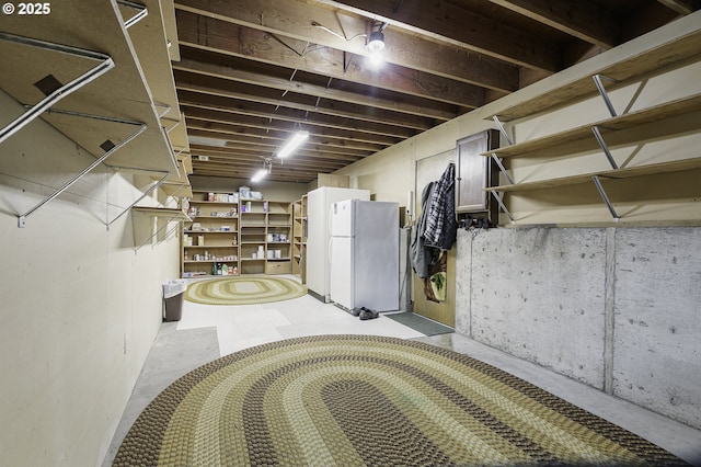 unfinished basement featuring freestanding refrigerator