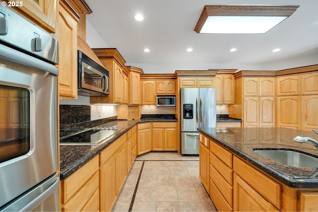 kitchen with a sink, recessed lighting, dark stone countertops, and stainless steel appliances