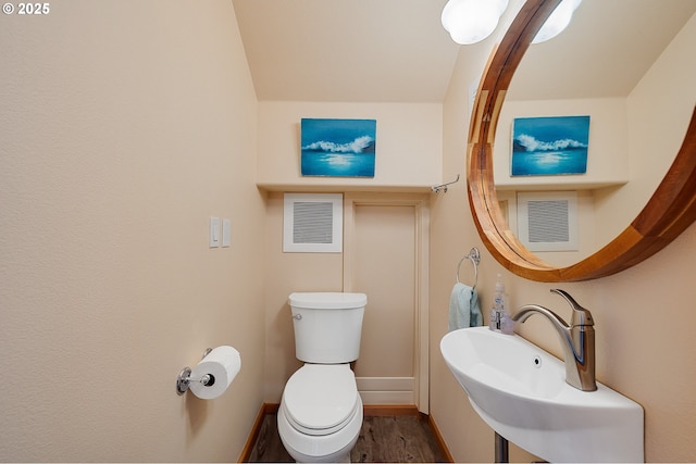 bathroom featuring baseboards, toilet, visible vents, a sink, and wood finished floors