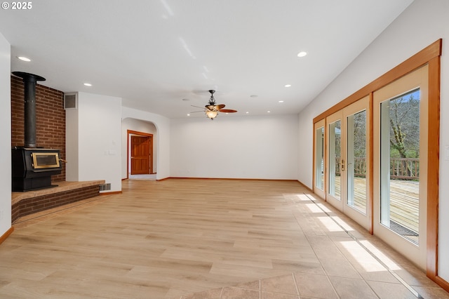 unfurnished living room featuring a wood stove, a wealth of natural light, recessed lighting, and ceiling fan
