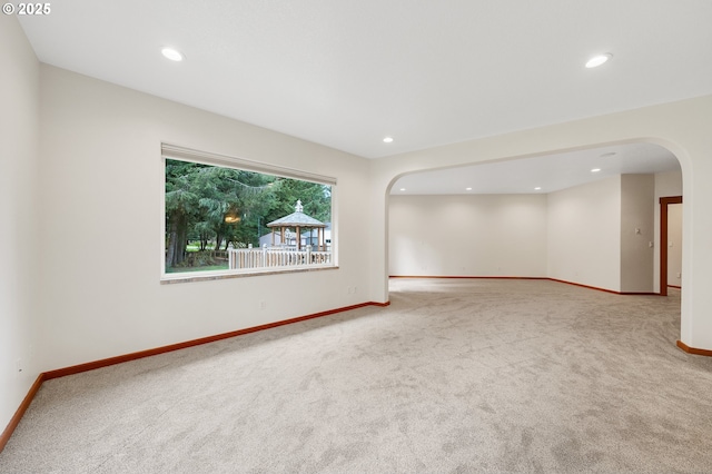 unfurnished room featuring arched walkways, baseboards, and carpet floors