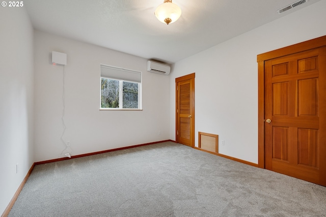 carpeted spare room with visible vents, baseboards, and a wall unit AC
