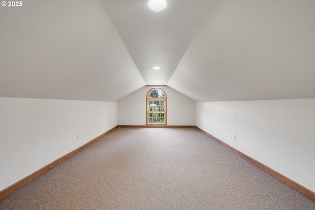 additional living space with baseboards, light colored carpet, and lofted ceiling