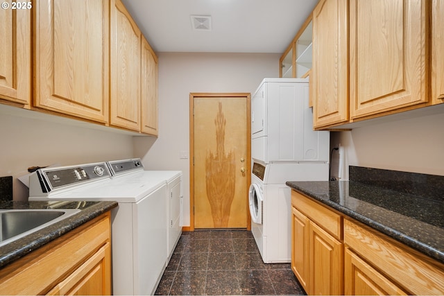 laundry room featuring baseboards, granite finish floor, visible vents, stacked washer / drying machine, and cabinet space