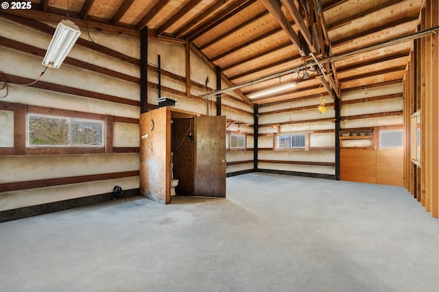 interior space featuring concrete floors, a garage, and vaulted ceiling
