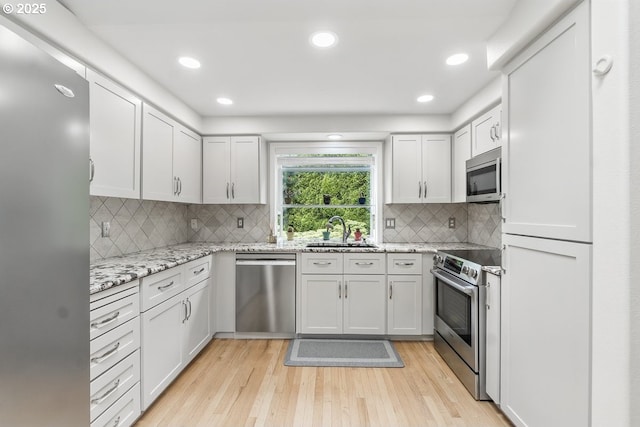 16485 SW Viking Ct, Beaverton, OR 97007 - kitchen with stainless steel appliances, a sink, light wood-style floors, light stone counters, and tasteful backsplash