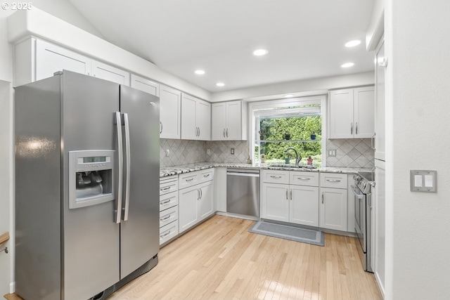 16485 SW Viking Ct, Beaverton, OR 97007 - kitchen featuring appliances with stainless steel finishes, light wood-style floors, a sink, tasteful backsplash, and light stone countertops
