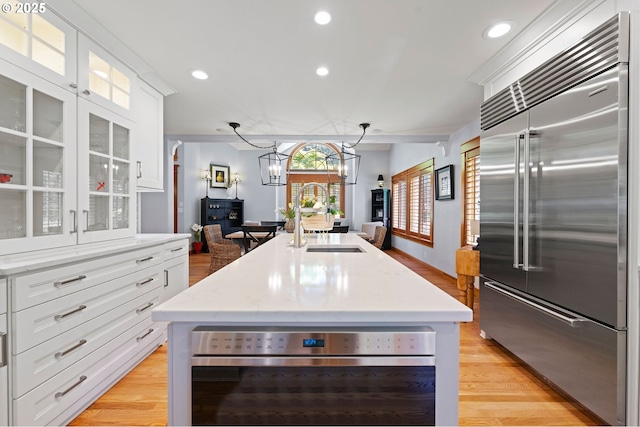1635 SW 14th St, Warrenton, OR 97146 - kitchen with appliances with stainless steel finishes, a sink, light wood finished floors, a kitchen island with sink, and white cabinetry