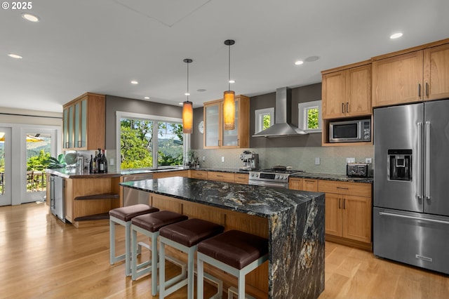 1524 Sherman Ave, Hood River, OR 97031 - kitchen with stainless steel appliances, wall chimney range hood, light wood-style flooring, tasteful backsplash, and dark stone counters