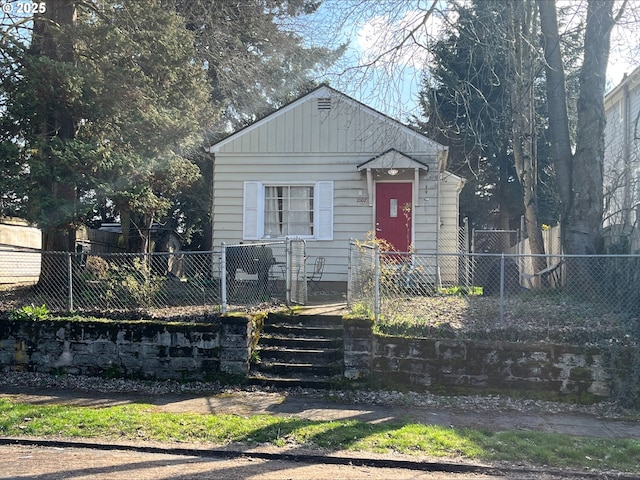 bungalow-style home featuring a fenced front yard and board and batten siding