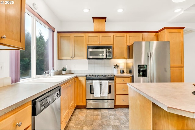 kitchen with a sink, appliances with stainless steel finishes, decorative backsplash, and light countertops