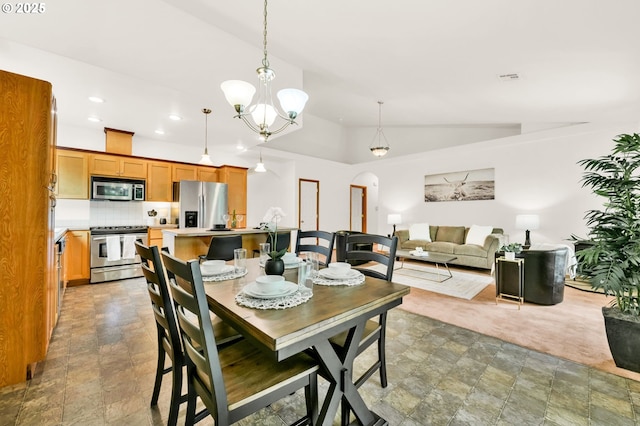 dining area featuring an inviting chandelier, arched walkways, stone finish floor, recessed lighting, and vaulted ceiling