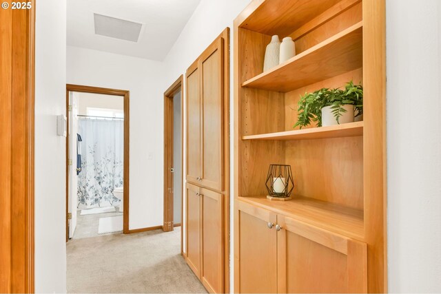 corridor featuring baseboards and light carpet