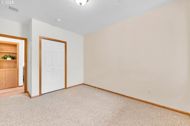 unfurnished bedroom featuring baseboards, light colored carpet, and visible vents