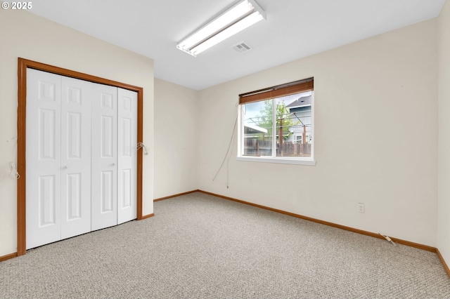 unfurnished bedroom with carpet flooring, baseboards, visible vents, and a closet