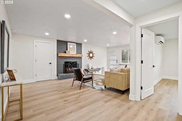 living room featuring light hardwood / wood-style flooring, a fireplace, and a wall unit AC