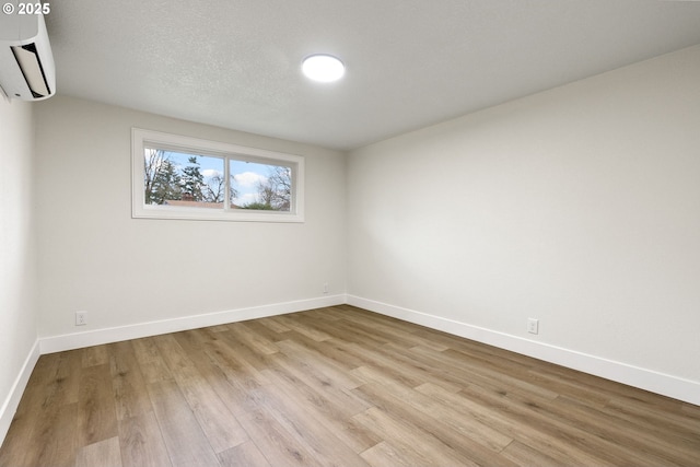 empty room with light hardwood / wood-style floors and a wall mounted air conditioner