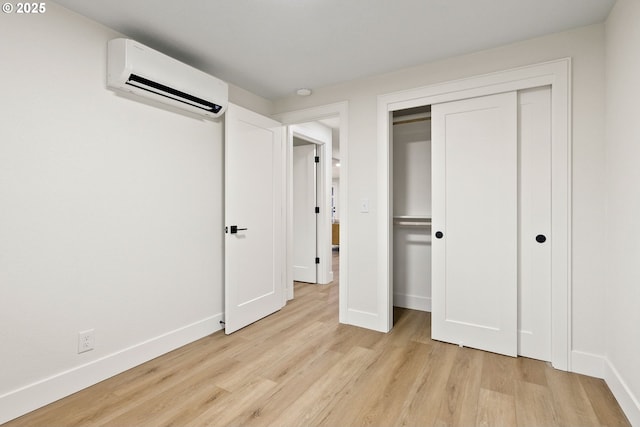 unfurnished bedroom with a closet, a wall mounted air conditioner, and light wood-type flooring