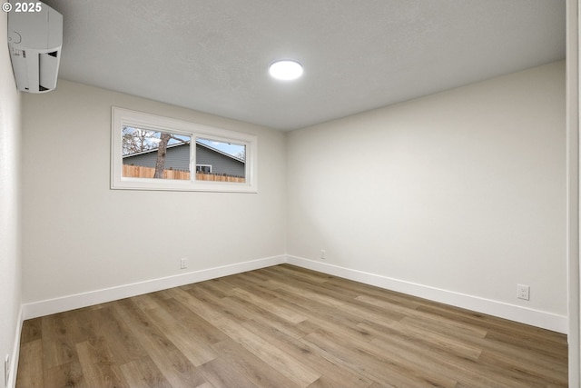 unfurnished room featuring light wood-type flooring and a wall mounted AC