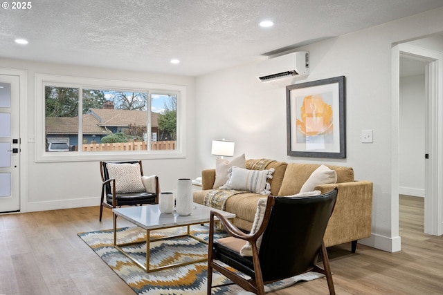 living room featuring a textured ceiling, a wall mounted AC, and light wood-type flooring