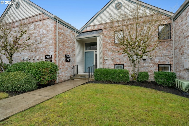 view of front of home featuring brick siding, central AC, and a front yard