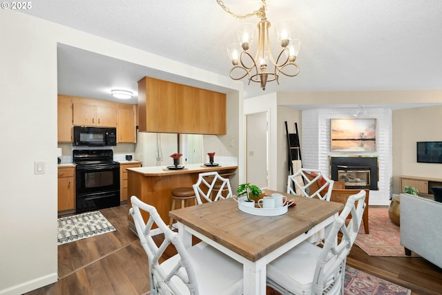 16146 SW 130th Ter Unit 2, Portland, OR 97224 - dining space with dark wood finished floors, a brick fireplace, and a chandelier