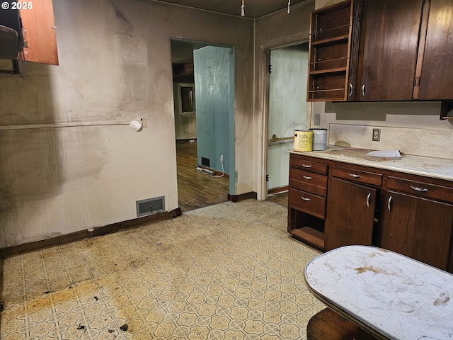 kitchen with visible vents, baseboards, open shelves, light countertops, and dark brown cabinetry