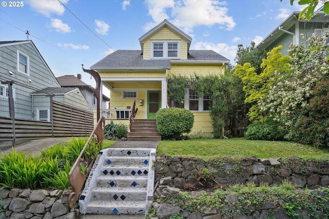 view of front of house featuring a shingled roof, a porch, and a front yard