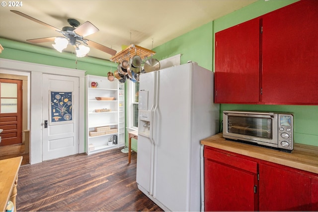 kitchen featuring ceiling fan, white refrigerator with ice dispenser, a toaster, dark wood-type flooring, and red cabinets