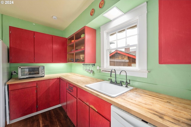 kitchen featuring a sink, red cabinets, wooden counters, and a toaster