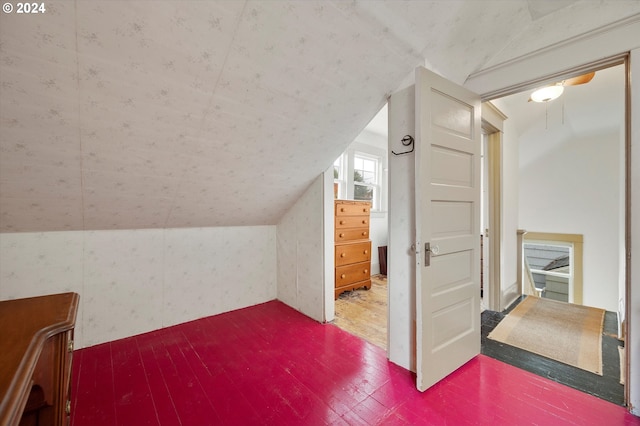 additional living space with wallpapered walls, vaulted ceiling, and hardwood / wood-style floors