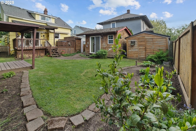 back of property with a storage unit, a deck, a fenced backyard, a lawn, and an outdoor structure
