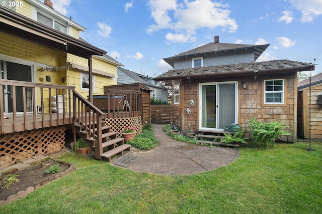 rear view of property featuring a yard and a deck