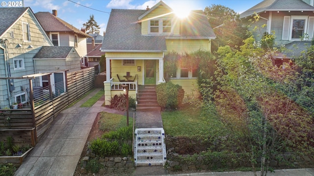 view of front facade featuring covered porch, stairs, and roof with shingles