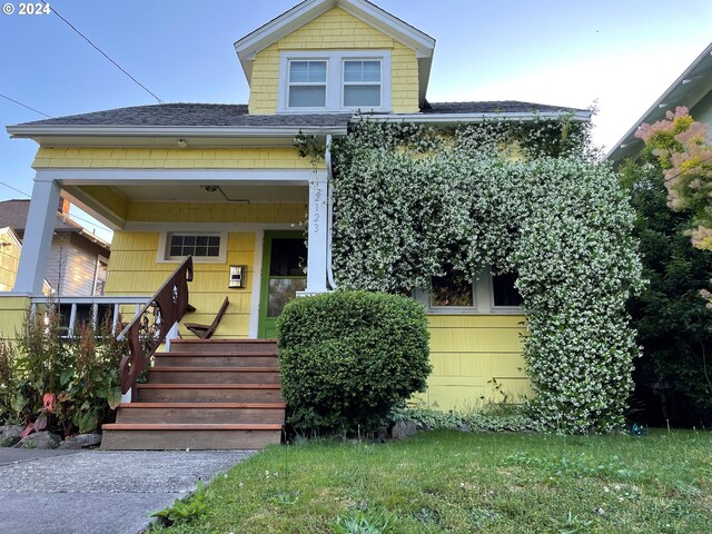 view of front facade featuring a shingled roof and covered porch