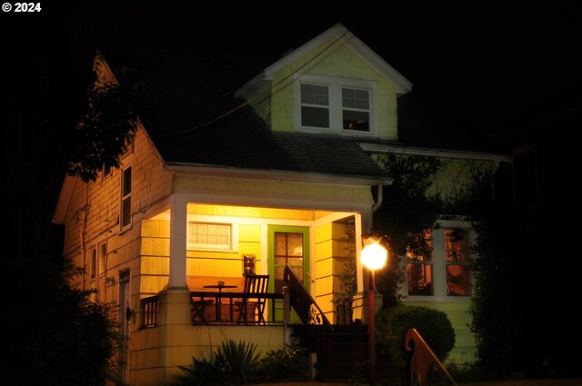 view of front of house featuring stairs, a shingled roof, and covered porch