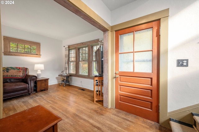 foyer featuring baseboards, wood finished floors, visible vents, and a healthy amount of sunlight