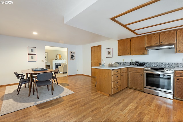 kitchen featuring under cabinet range hood, brown cabinets, light countertops, and stainless steel range with electric stovetop