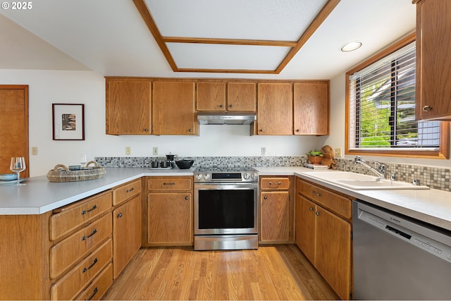 kitchen featuring light wood-type flooring, a sink, light countertops, a peninsula, and stainless steel appliances