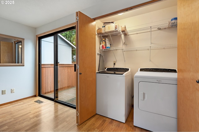 washroom featuring laundry area, visible vents, wood finished floors, baseboards, and washing machine and clothes dryer