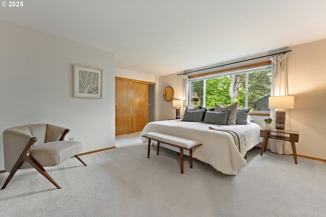 bedroom featuring light colored carpet, baseboards, and a closet