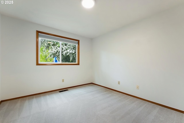 unfurnished room with baseboards, visible vents, and light colored carpet