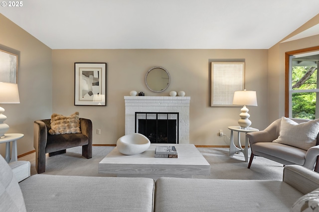 living area featuring baseboards, a brick fireplace, and light colored carpet