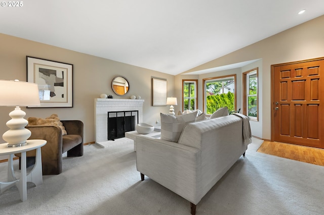 living room with lofted ceiling, recessed lighting, a brick fireplace, and light colored carpet