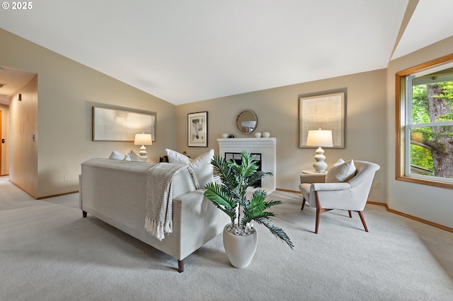 living room with baseboards, a fireplace, vaulted ceiling, and light colored carpet