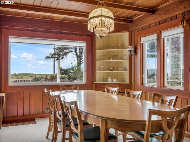 1021 S Prom, Seaside, OR 97138 - dining space with wooden ceiling with exposed beams, wooden walls, plenty of natural light, a chandelier, and carpet