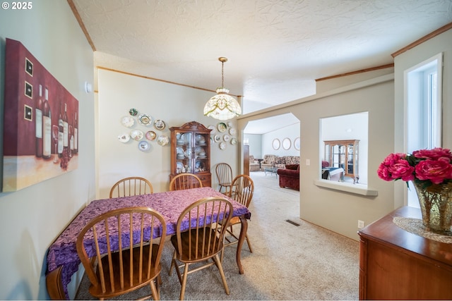 dining area with carpet floors, a textured ceiling, a chandelier, and ornamental molding